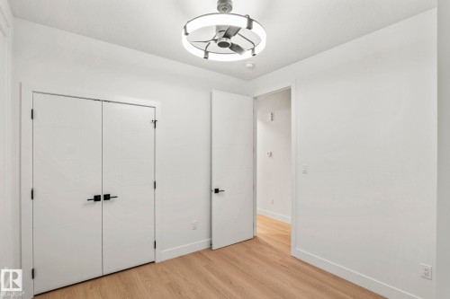 Hardwood-finish flooring, white paneled doors with matte black hardware, and a modern ceiling fan with integrated lighting - 13111 187 Avenue Nw, Edmonton, AB - Indoor Photo Showing Other Room