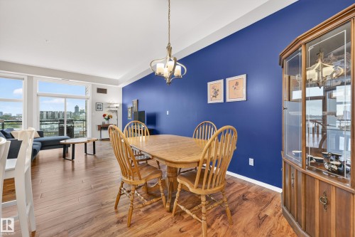 Spacious living area featuring wood-finish flooring, a vibrant accent wall, and expansive windows providing abundant natural light - 410 10531 117 Street, Edmonton, AB 