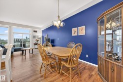 Spacious living area featuring wood-finish flooring, a vibrant accent wall, and expansive windows providing abundant natural light - 