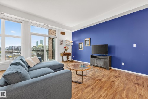 Expansive living area featuring wood-finish flooring and a bold accent wall - 410 10531 117 Street, Edmonton, AB 