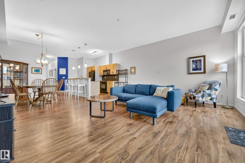 Spacious living area featuring wood-finish flooring, high ceilings, and recessed lighting - 410 10531 117 Street, Edmonton, AB 