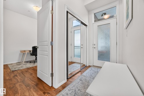 Entryway featuring wood-finish flooring, a full-lite door with frosted glass, and a transom window - 410 10531 117 Street, Edmonton, AB 