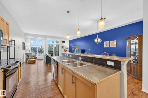 Open-concept living space featuring wood-finish flooring and ample natural light from large windows - 410 10531 117 Street, Edmonton, AB 