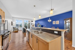 Open-concept living space featuring wood-finish flooring and ample natural light from large windows - 