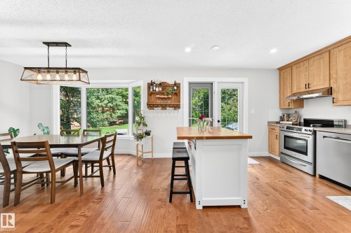 Open-concept kitchen and dining area featuring wood-finish flooring, recessed lighting, and a bay window - 15146 Ramsay Crescent, Edmonton, AB 