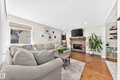 Living space featuring wood-finish flooring, a stone-faced fireplace with a wood mantle, and recessed lighting - 15146 Ramsay Crescent, Edmonton, AB 