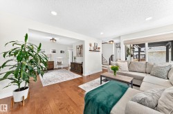 Open-concept living space featuring wood-finish flooring, recessed lighting, and a large window with a built-in blind - 