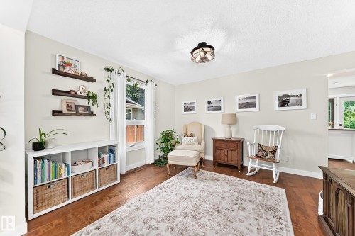Spacious room featuring wood-finish flooring, light-toned wall paint, and a ceiling-mounted light fixture - 15146 Ramsay Crescent, Edmonton, AB 