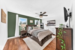 Bedroom featuring rich wood-finish flooring, a contemporary ceiling fan, and multiple windows - 