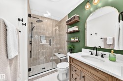 Bathroom featuring a glass-enclosed shower with vertical tile surround and built-in niche, a rainfall showerhead, and a wall-mounted shower wand - 