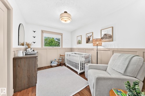 Bright room featuring panel wainscoting and warm wood-finish flooring - 15146 Ramsay Crescent, Edmonton, AB 