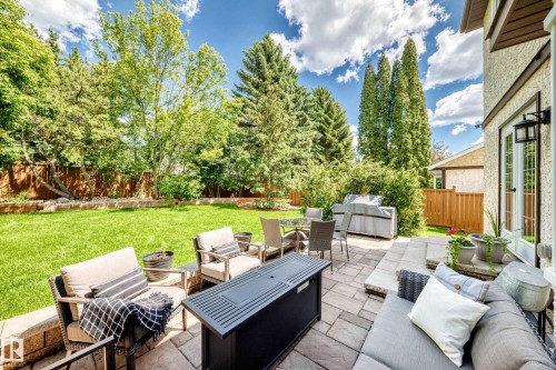 Expansive backyard featuring a large paved patio, terraced landscaping, mature trees, and a well-maintained lawn - 15146 Ramsay Crescent, Edmonton, AB 