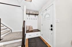 Entryway featuring a built-in bench with storage drawers, shiplap accent wall, and integrated coat hooks - 