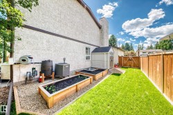 Private backyard featuring a manicured lawn, raised garden beds, and a wood fence - 