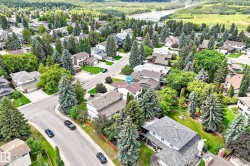 Residential neighborhood featuring mature trees, paved streets, and a river in the distance - 