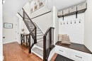 Entryway featuring wood-finish flooring, a carpeted staircase with dark wood newel posts and railings, and a built-in bench with storage drawers - 15146 Ramsay Crescent, Edmonton, AB 