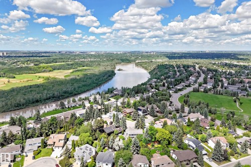 Expansive aerial capturing a river winding through a forested landscape, bordered by residential neighborhoods featuring mature trees and a manicured green space - 15146 Ramsay Crescent, Edmonton, AB 
