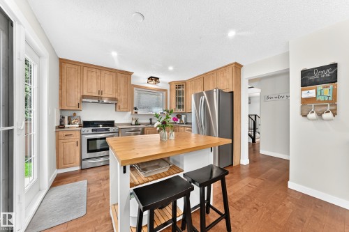 Kitchen featuring light wood cabinetry, stainless steel appliances, and a central island with a wood countertop - 15146 Ramsay Crescent, Edmonton, AB 