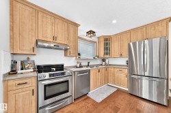 Kitchen featuring wood cabinetry, stainless steel appliances, corner sink, and wood-finish flooring - 