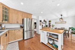 Light wood cabinetry complemented by a stainless steel refrigerator and wood-finish flooring - 