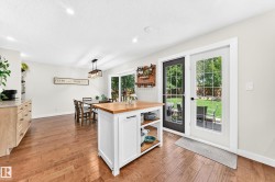 Spacious interior featuring wood-finish flooring, a kitchen island with a wood countertop, and built-in cabinetry with a light-toned countertop - 
