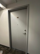 Solid core entry door with matte silver hardware, peephole, and apartment number plate - 