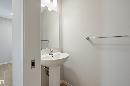 Pedestal sink with a chrome faucet, large vanity mirror, and linear light fixture - 56 Springbrook Wynd, Spruce Grove, AB - Indoor Photo Showing Bathroom