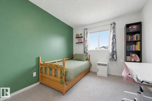 Bedroom featuring a green accent wall, light-toned carpeting, and a white framed window - 56 Springbrook Wynd, Spruce Grove, AB - Indoor Photo Showing Bedroom