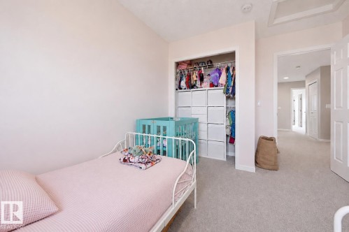 Plush carpeting and a neutral color palette define this room, featuring an open closet with integrated storage cubes and hanging rods - 56 Springbrook Wynd, Spruce Grove, AB - Indoor Photo Showing Bedroom