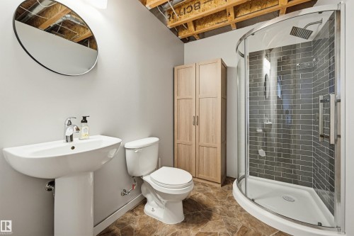Modern bathroom featuring a pedestal sink with chrome faucet, a white toilet, and a curved glass shower enclosure with subway tile surround and a rain showerhead - 56 Springbrook Wynd, Spruce Grove, AB - Indoor Photo Showing Bathroom