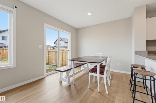 Dining area featuring wood-finish flooring, a large window, and a sliding glass door providing access to the backyard - 56 Springbrook Wynd, Spruce Grove, AB - Indoor Photo Showing Dining Room