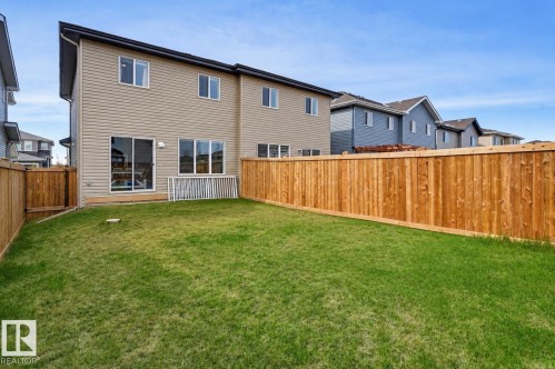 Spacious backyard featuring a manicured lawn, full wood privacy fencing, and a light-colored vinyl siding exterior - 56 Springbrook Wynd, Spruce Grove, AB - Outdoor