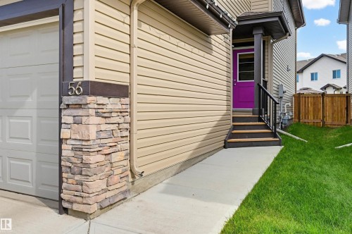 Property exterior featuring horizontal siding, a vibrant purple entry door, a stone-clad pillar with house numbers, and a single-car garage door - 56 Springbrook Wynd, Spruce Grove, AB - Outdoor