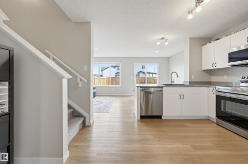 Kitchen featuring stainless steel appliances, white cabinetry, dark countertops, and a single-basin sink with a gooseneck faucet - 56 Springbrook Wynd, Spruce Grove, AB - Indoor Photo Showing Kitchen