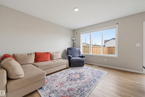 Spacious living area featuring light wood-finish flooring, neutral wall paint, and a large window - 56 Springbrook Wynd, Spruce Grove, AB - Indoor Photo Showing Living Room