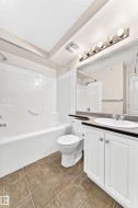 Full bathroom featuring a white tub/shower combination, white toilet, and a vanity with white cabinetry - 