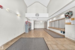 Building entry hall featuring high vaulted ceilings, neutral-toned tile flooring, sconce lighting, and a mail center with individual boxes - 