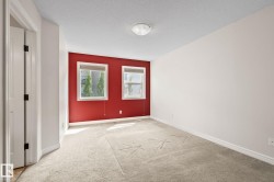 Carpeted interior space featuring a bold red accent wall with two windows - 