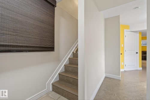 Staircase featuring tile treads and risers, white handrail, and a woven wood shade - 39 Meadowview Court, Spruce Grove, AB 
