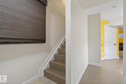 Staircase featuring tile treads and risers, white handrail, and a woven wood shade - 