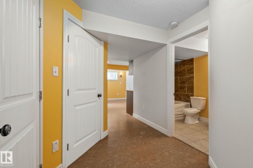 Hallway featuring wood-finish flooring, crisp white trim, and a warm yellow wall - 39 Meadowview Court, Spruce Grove, AB 