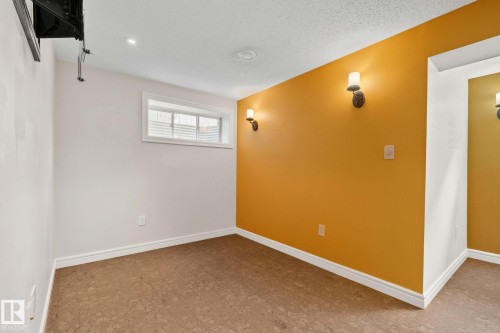 Room featuring a mix of white and warm-toned accent walls, wall-mounted sconce lighting, a window with horizontal blinds, textured ceiling, and patterned resilient flooring - 39 Meadowview Court, Spruce Grove, AB 