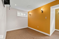 Room featuring a mix of white and warm-toned accent walls, wall-mounted sconce lighting, a window with horizontal blinds, textured ceiling, and patterned resilient flooring - 