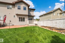 Expansive backyard featuring a manicured lawn, stamped concrete patio, and a wooden privacy fence - 