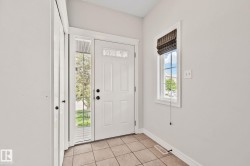 Entryway featuring a white paneled door with decorative glass, sidelights, and transom window - 