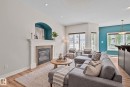 Living area featuring a fireplace with a white mantel and tile surround, recessed lighting, wood-finish flooring, multiple windows, and a distinctive accent wall - 39 Meadowview Court, Spruce Grove, AB 