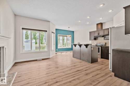 Open-concept living area featuring wood-finish flooring, recessed lighting, and a prominent kitchen island with seating - 39 Meadowview Court, Spruce Grove, AB 