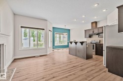Open-concept living area featuring wood-finish flooring, recessed lighting, and a prominent kitchen island with seating - 