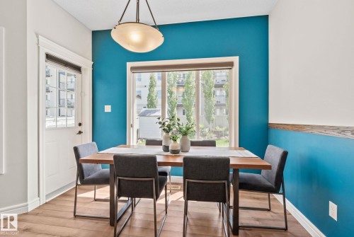 Dining area featuring wood-finish flooring, a contemporary overhead light fixture, and a large window with exterior views - 39 Meadowview Court, Spruce Grove, AB 