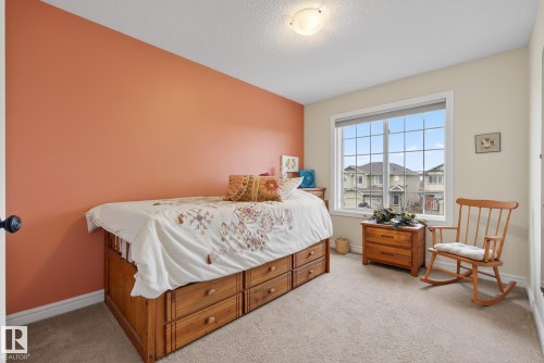 Carpeted room featuring a large window with white framing, light-colored walls, a single accent wall, and a flush-mount ceiling light fixture - 39 Meadowview Court, Spruce Grove, AB 